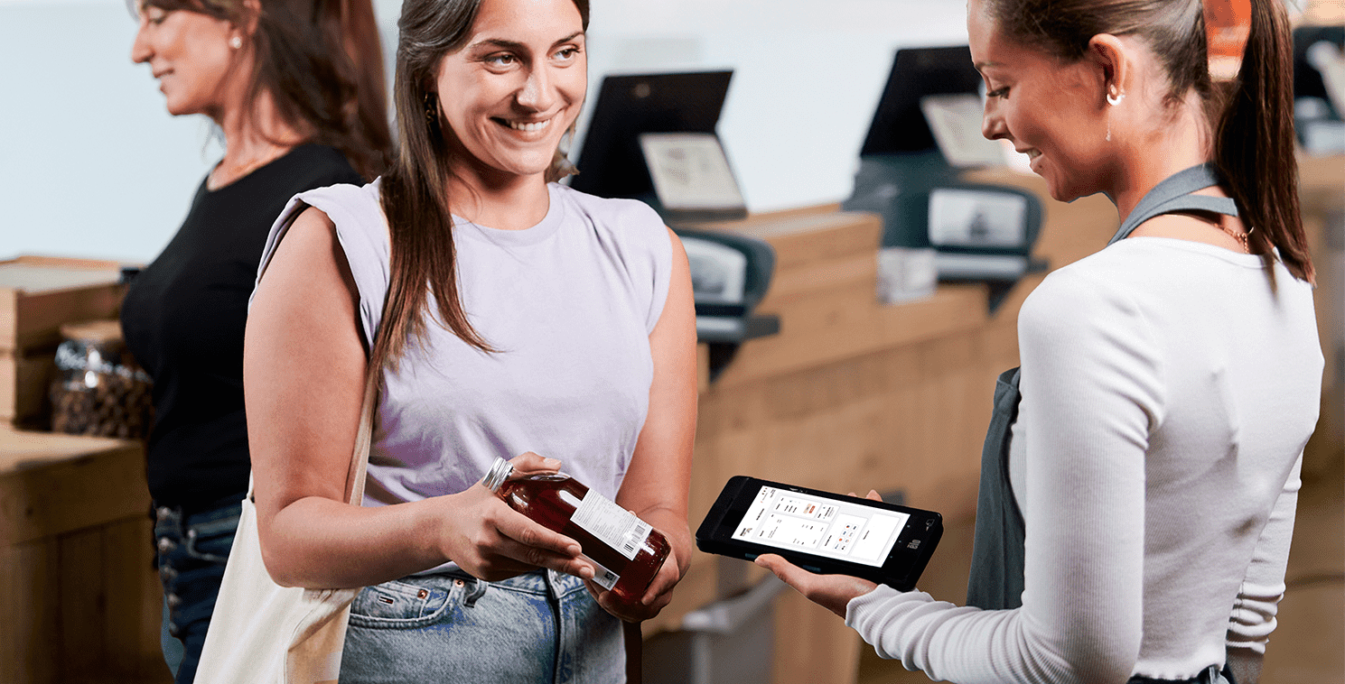 Deux clients utilisent un grand écran tactile en magasin pour explorer des vêtements virtuels, mettant en valeur la technologie immersive en point de vente et l’engagement personnalisé en boutique.